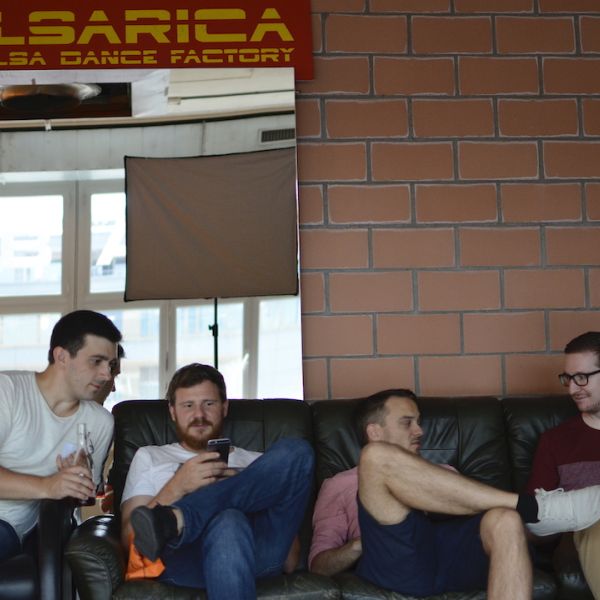 Vier Männer sitzen auf Sofa und machen Pause nach einer Salsatanzstunde