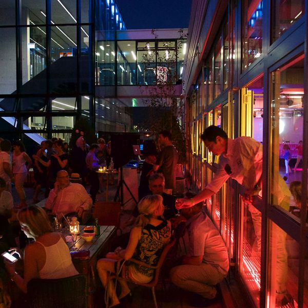 Partylocation auf einer Dachterrasse mit vielen Personen die sitzen und etwas Trinken