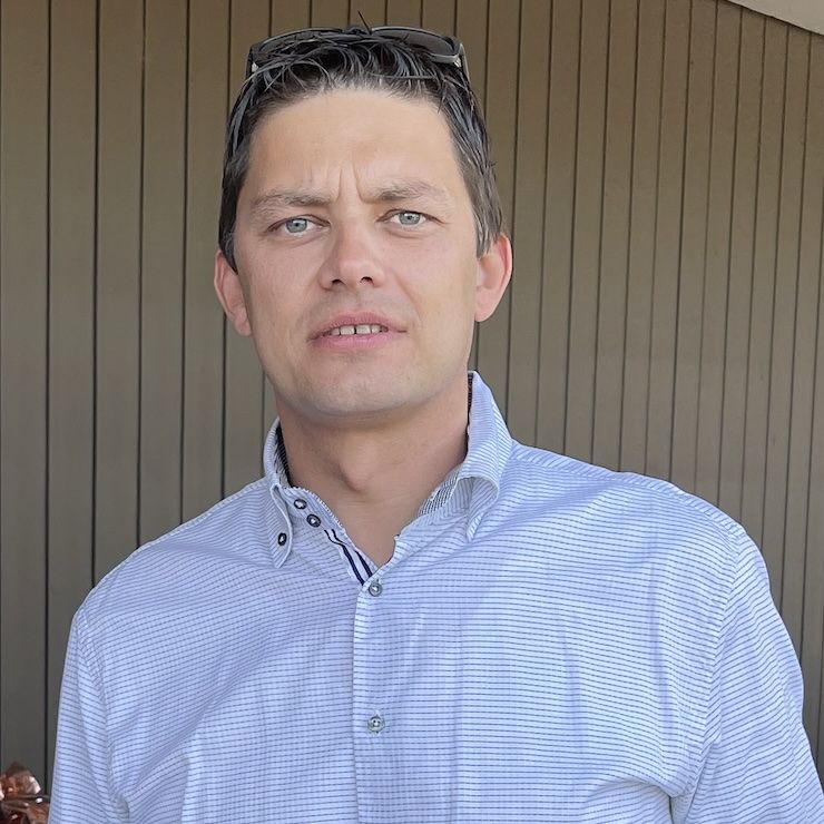 Herr mit blauem Hemd vor einer Holzwand