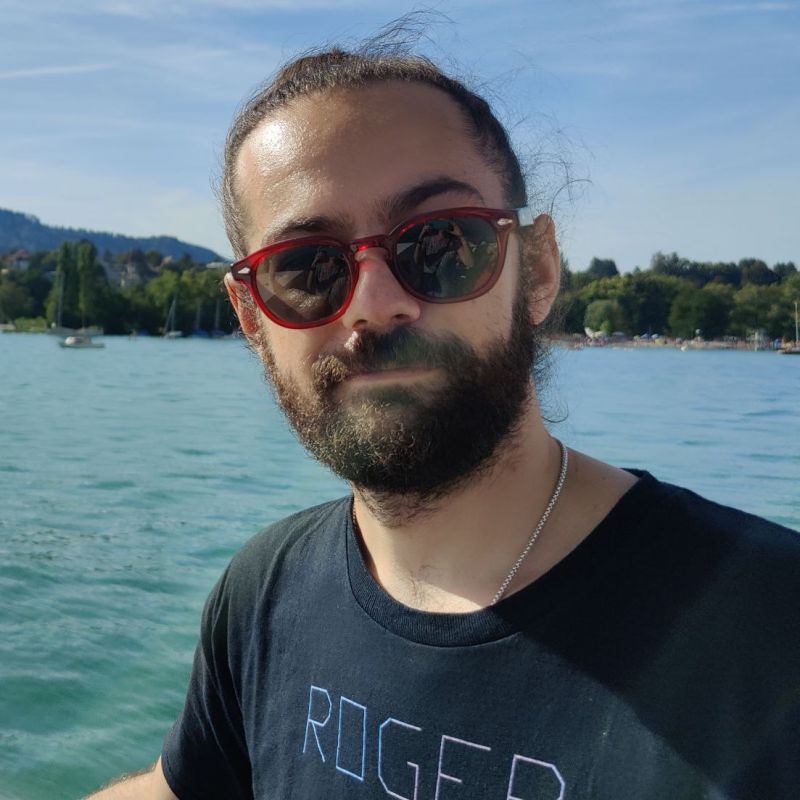 Junger Mann mit Bart und Sonnenbrille auf dem See