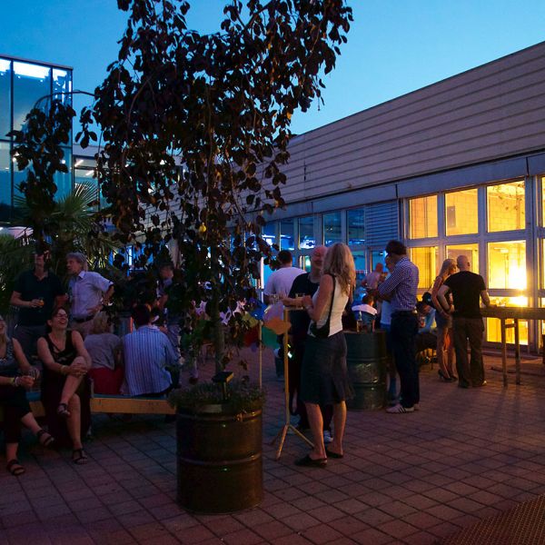 Gemütliche Dachterrasse in abendlicher Stimmung mit Personen die sich unterhalten