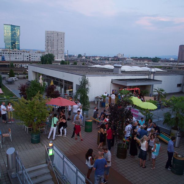 Sommerliche Dachterrasse mit vielen Personen die gemütlich sitzen und etwas Trinken