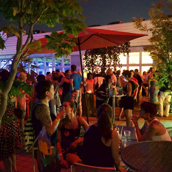 Partylocation auf einer Dachterrasse mit vielen Personen die sitzen und etwas Trinken