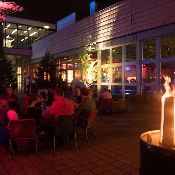 Sommerliche Dachterrasse mit vielen Personen die gemütlich sitzen und etwas Trinken