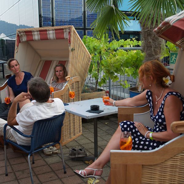 Sommerliche Dachterrasse mit vielen Personen die gemütlich sitzen und etwas Trinken