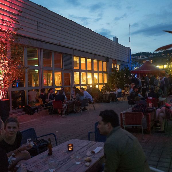 Sommerliche Dachterrasse mit vielen Personen die gemütlich sitzen und etwas Trinken