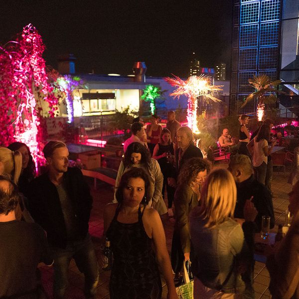 Sommerliche Dachterrasse mit vielen Personen die gemütlich etwas Trinken