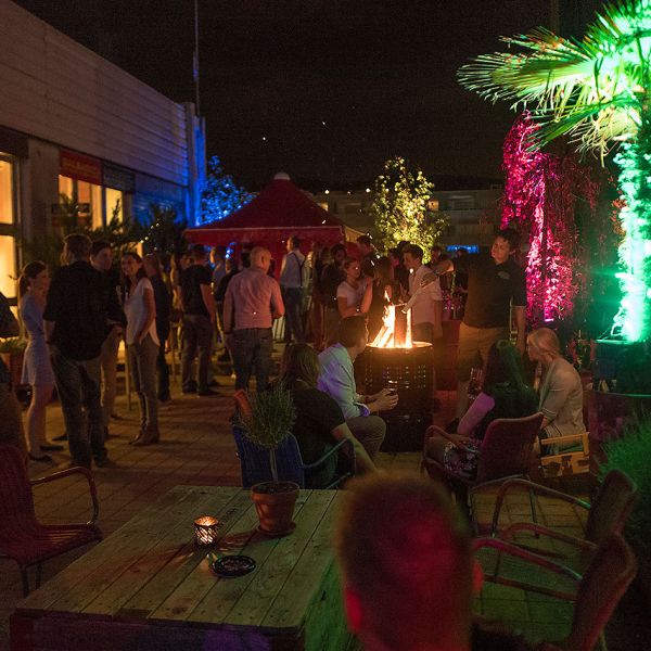 Sommerliche Dachterrasse mit vielen Personen die gemütlich sitzen und etwas Trinken