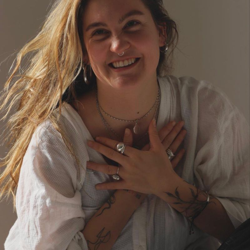 junge frau mit langen gewellten blonden Haaren, Hände überkreuzt und lachend