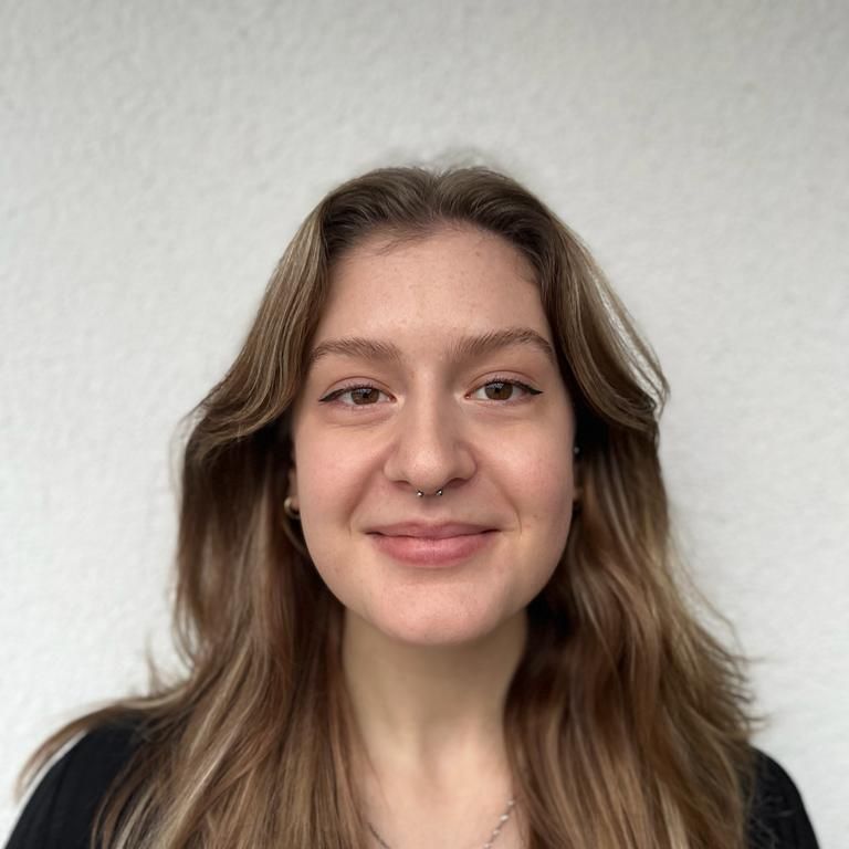 Porträtfoto von einer Frau mit langen hellbraunen Haaren vor einer weissen Wand