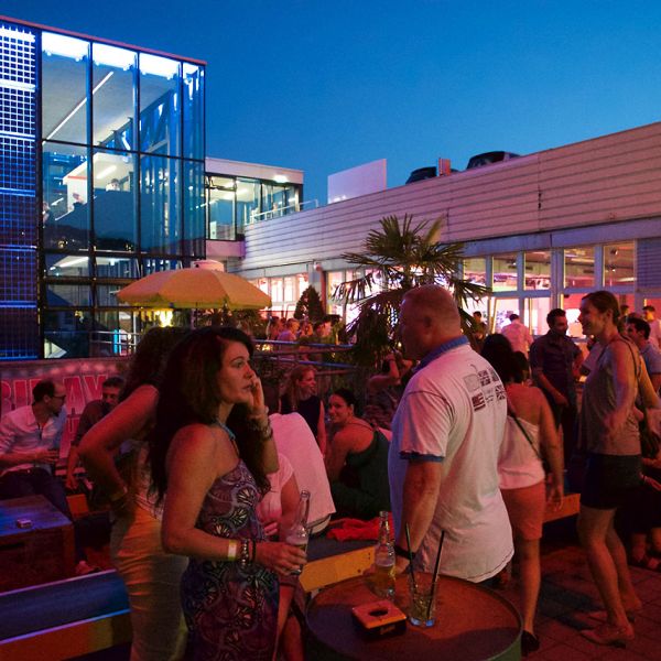 Sommerliche Dachterrasse mit vielen Personen die gemütlich etwas Trinken