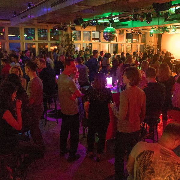 Sommerliche Dachterrasse mit vielen Personen die gemütlich etwas Trinken