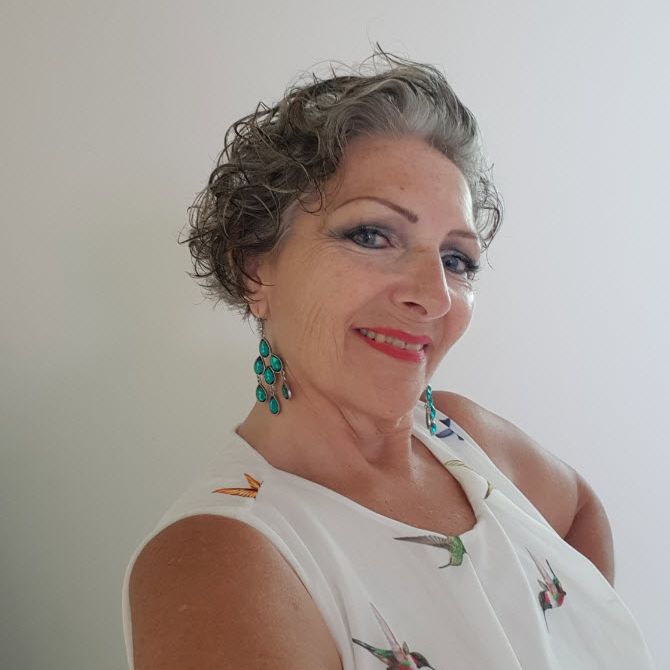 Frau mit rotem Lippenstift und schön geschminkt steht vor weisser Wand und posiert für ein Foto