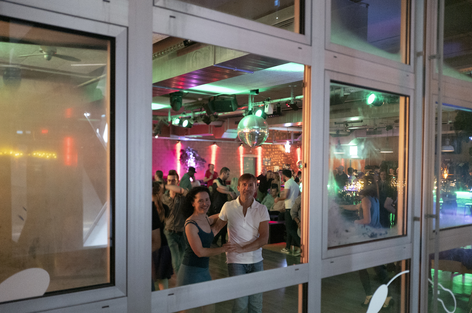 Offenes Fenster einer Tanzschule, man sieht ein tanzendes Paar das herausschaut