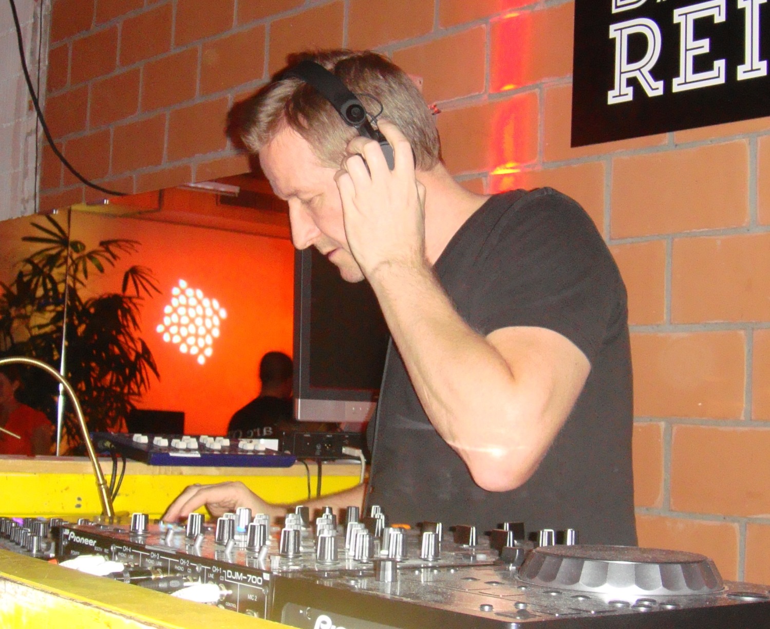 Mann mit hellen Haaren und Kopfhörer, der an einem Musikmischpult arbeitet