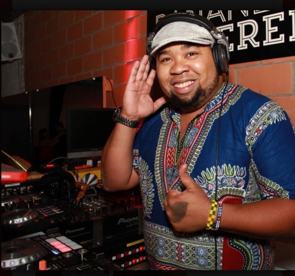 Mann mit Kopfhörer mit dunkelblauem T-Shirt der an einem Mischpult steht