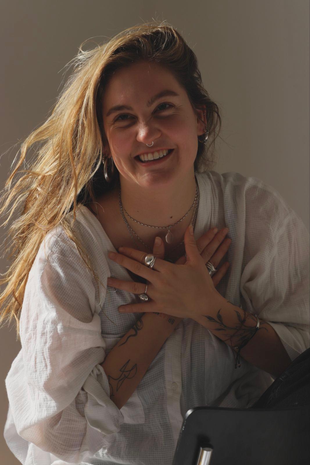 junge frau mit langen gewellten blonden Haaren, Hände überkreuzt und lachend