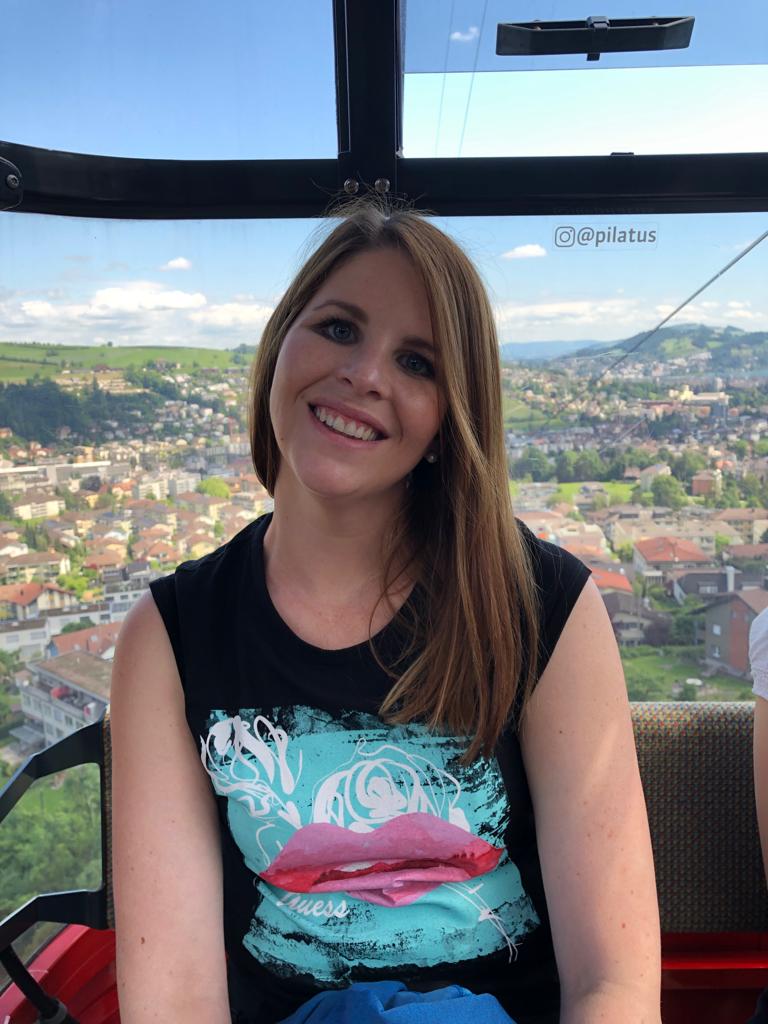 Frau sitzt in deiner Gondel und trägt ein kurzes Shirt. Sie trägt die Haare offen und lächelt in die Kamera