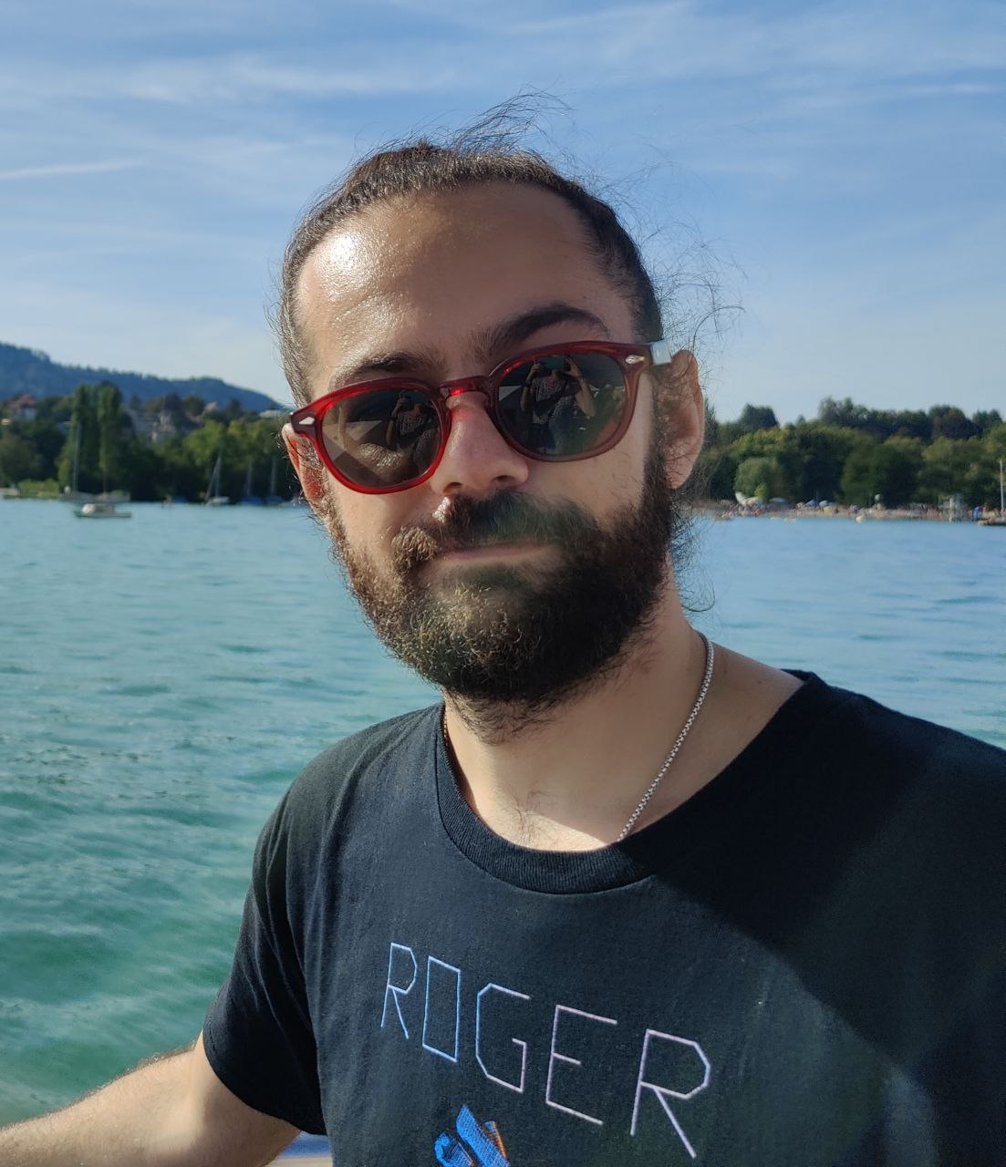 Junger Mann mit Bart und Sonnenbrille auf dem See