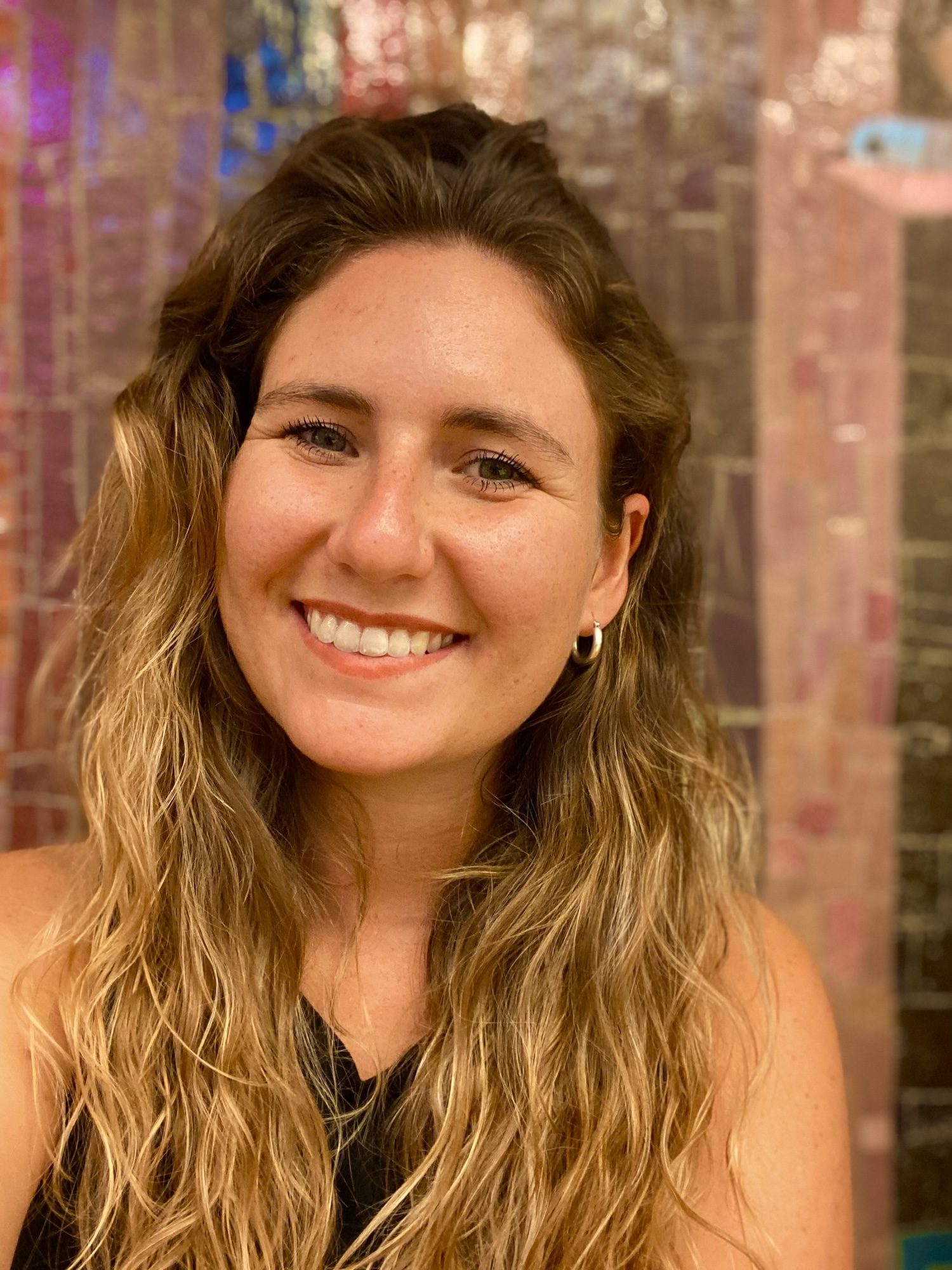 Junge Frau mit hellblonden gelockten Haaren und einem Lächeln